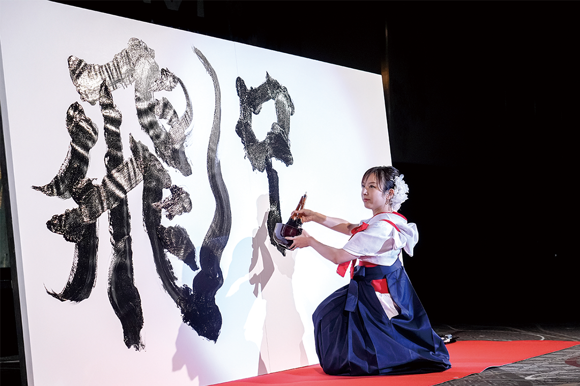 オープニングアクトで「飛躍」を揮毫した書道家／アーティストの青柳美扇氏。小柄な身体から生み出される力強い筆致に圧倒される